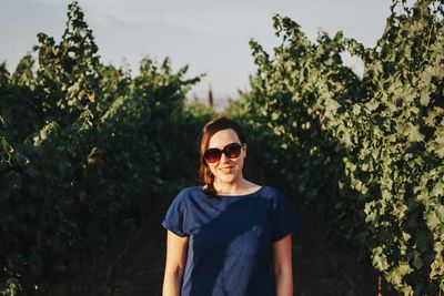 Portrait of smiling young woman standing against trees