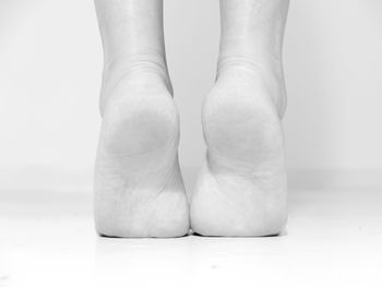 Low section of female ballet dancer dancing on floor against white background