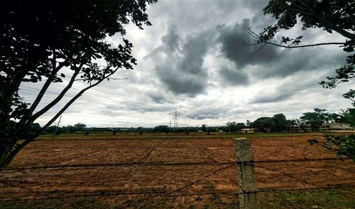 View of field against cloudy sky