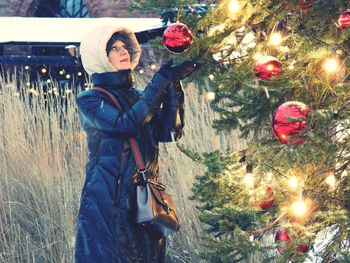 Rear view of woman standing against christmas tree