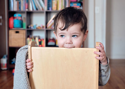 Young boy toddler is playing with his chair and making funny faces