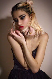 Beautiful young woman sitting against wall