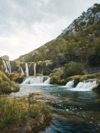 Scenic view of waterfall against sky