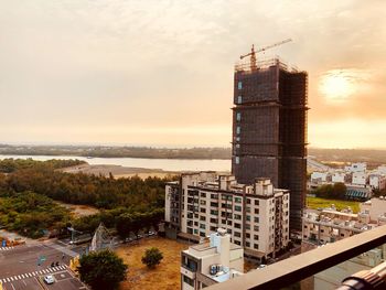 High angle view of buildings by sea against sky during sunset