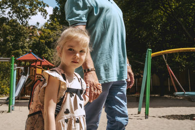 Portrait of girl holding hands while standing with grandfather at kindergarten