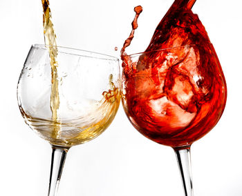 Close-up of wineglass on glass against white background