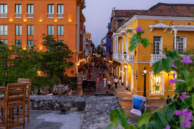 People on street amidst buildings in city at dusk