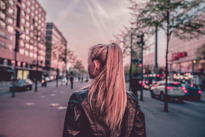 Portrait of young woman standing on street in city