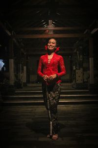 Portrait of woman standing against red wall