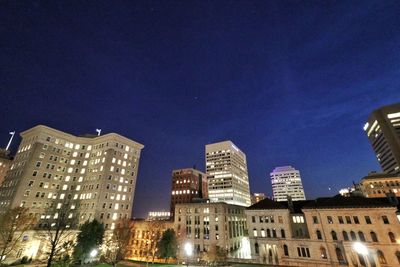 Low angle view of illuminated cityscape against blue sky