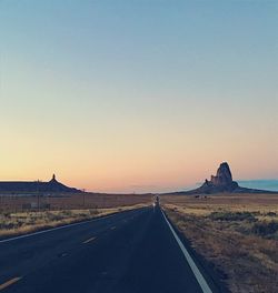 Empty road against clear sky at sunset