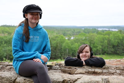 Portrait of young girls sitting on wall