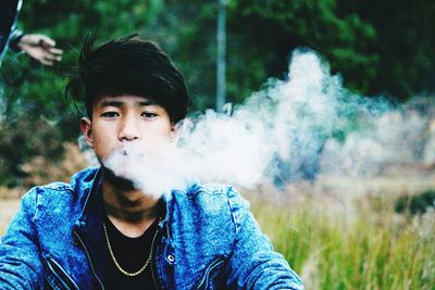 Portrait of young man smoking on field