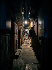 Empty alley amidst buildings in city at night