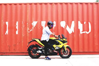 Man riding bicycle against red wall
