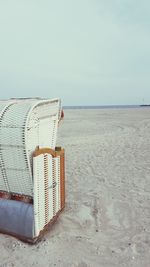 Hooded chairs on beach against clear sky