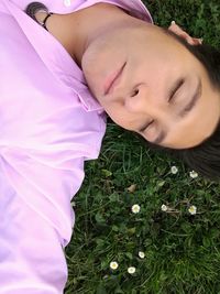 Close-up portrait of young woman lying on grass