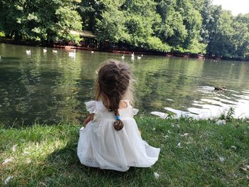 Rear view of woman by lake against trees