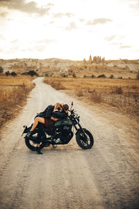 Man riding motorcycle on road against sky