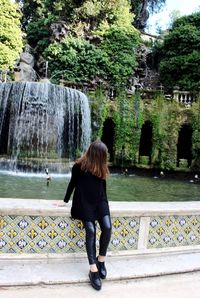 Rear view of woman standing against trees