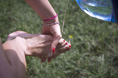 Midsection of woman holding hands on field