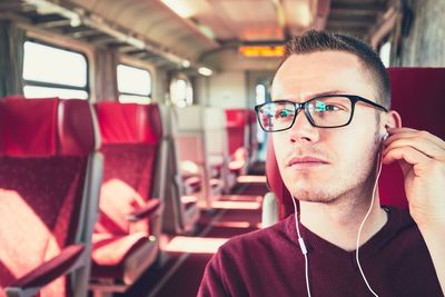 Young man listening to music while traveling in bus