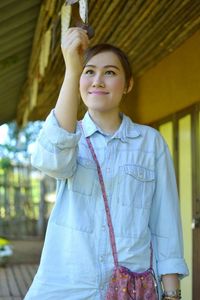 Close-up of smiling woman looking at decoration while standing at porch