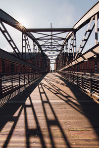 Metallic footbridge against sky during sunny day