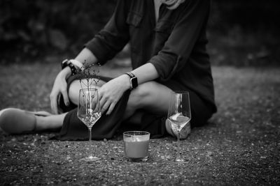 Midsection of man holding drink while sitting outdoors