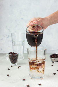 Pouring espresso into a tall glass with tonic and ice. making tonic iced coffee. summer drink.