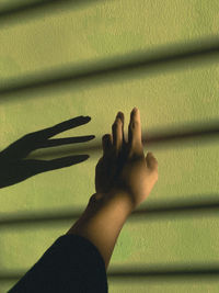 Low section of person touching shadow on wall