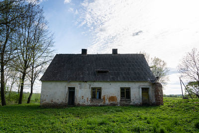 Abandoned house on field against sky