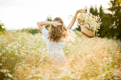 Rear view of woman with pink flowers on field