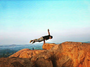 Man standing on rock against sky