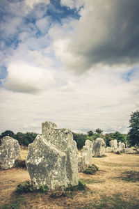 Rocks on field against cloudy sky