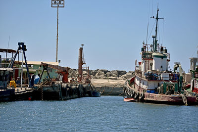 Sailboats moored at harbor against clear sky