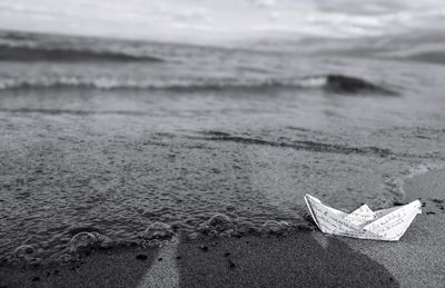 Close-up of paper on beach against sky