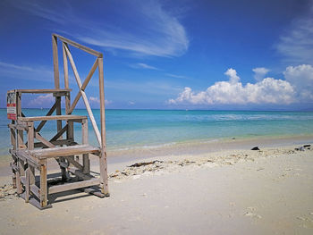 Lifeguard hut on beach against blue sky