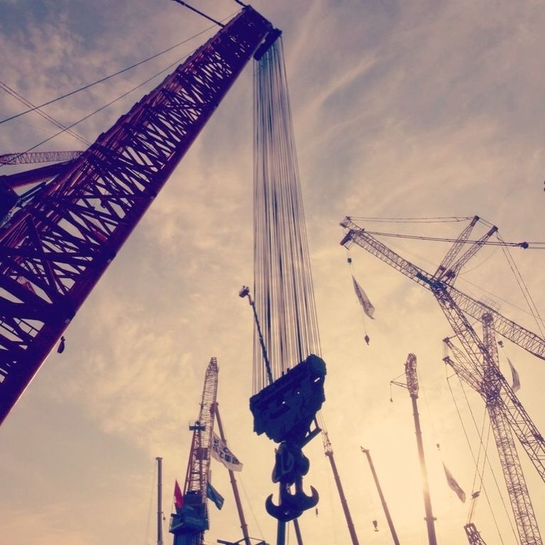 low angle view, sky, amusement park, cloud - sky, amusement park ride, arts culture and entertainment, construction site, ferris wheel, crane - construction machinery, cloudy, development, tall - high, cloud, built structure, outdoors, construction industry, metal, no people, day, crane