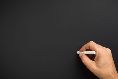 Close-up of hand holding paper over black background