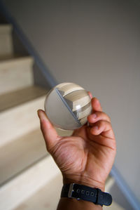 Cropped hand of man holding crystal ball against staircase