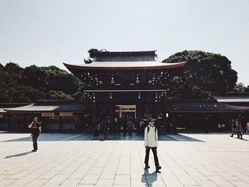 Rear view of people standing outside temple against clear sky