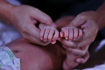 Close-up of mother holding hands of baby 