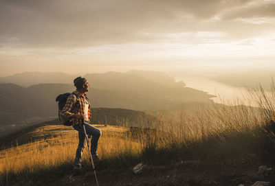 Mature man holding hiking pole looking at sunrise