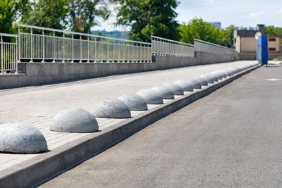 The pedestrian sidewalk is separated from the carriageway by concrete hemispheres to prevent parking