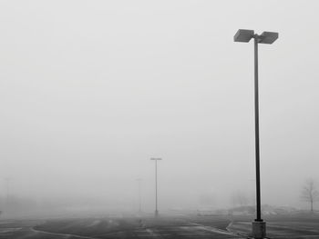 Street light on road against sky in foggy weather
