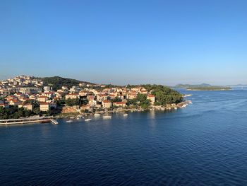 Townscape by sea against clear blue sky