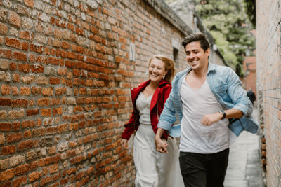 Smiling couple running in alley