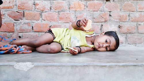 Portrait of cute boy lying on wall