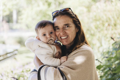 Portrait of grandmother holding baby outside